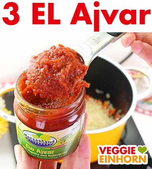 Nahaufnahme von einem Esslöffel mit Ajvar und einem Glas Ajvar.