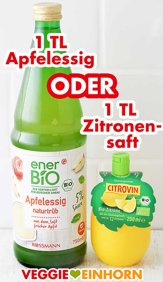 Apfelessig oder Zitronensaft Eine Flasche Apfelessig und eine Plastikzitrone mit Zitronensaft