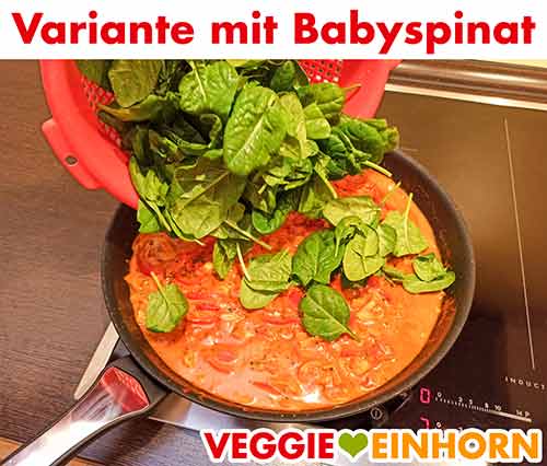Zufügen des Babyspinats zum Paprika Curry Baby-Blattspinat wird in die Pfanne zum Paprikacurry zugefügt