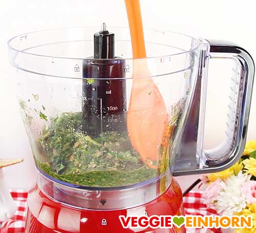 Bärlauchpesto am Rand der Küchenmaschine mit einem Silikonlöffel runterschieben Bärlauchpesto am Rand der Küchenmaschine mit einem Silikonlöffel runterschieben