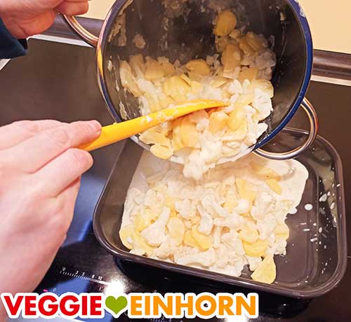 Den Topfinhalt in eine Auflaufform geben. Kartoffeln und Blumenkohl werden aus dem Topf in die Auflaufform geschüttet.