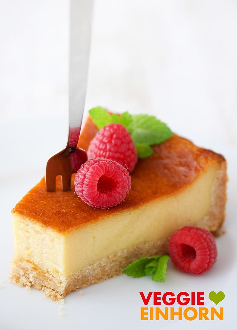 Eine Kuchengabel in einem Stück veganem Käsekuchen Der beste vegane Käsekuchen serviert mit Himbeeren