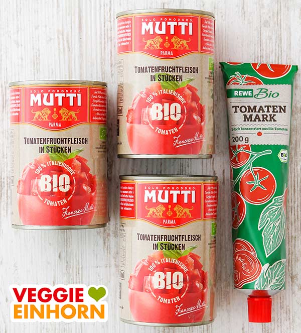 Drei Dosen mit Tomatenstücken und eine Tube Tomatenmark