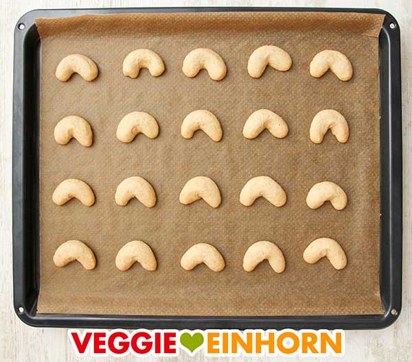 Gebackene Vanillekipferl auf einem Backblech mit Backpapier