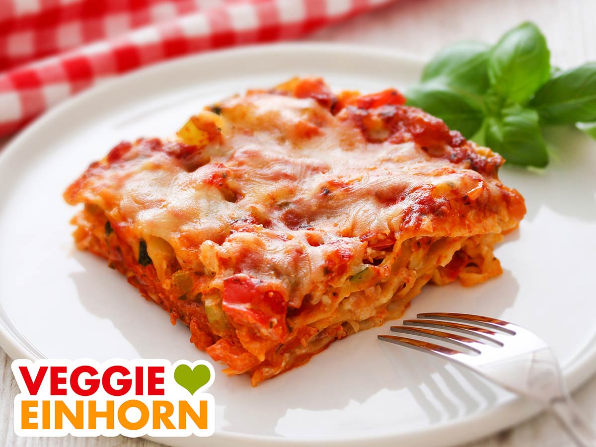 Eine Portion Gemüselasagne mit veganer Crème fraîche auf einem Teller
