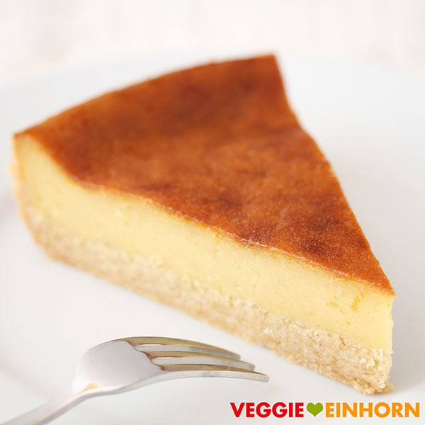 Bester veganer Käsekuchen mit einer Kuchengabel Ein Stück veganer Käsekuchen auf einem Kuchenteller