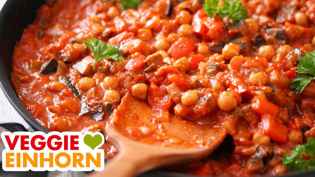 Auberginen Paprika Pfanne mit einem Pfannenwender aus Holz Auberginen Paprika Pfanne mit Kichererbsen und Petersilie
