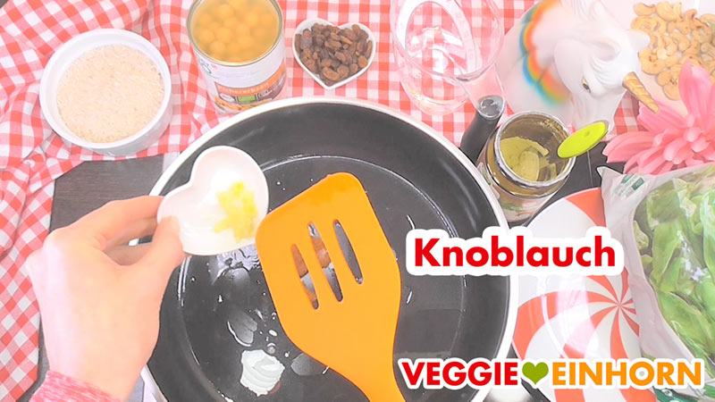 Durchgepresster Knoblauch wird zugefügt. Die gepresste Knoblauchzehe wird in die Pfanne gegeben.