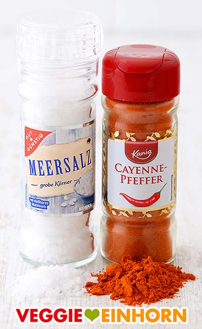 Salz und Cayennepfeffer Eine Mühle mit Meersalz und ein Streuer mit Cayennepfeffer