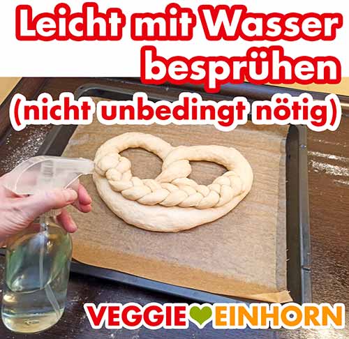 Mit einer Sprühflasche aus Glas besprühen Die Neujahrsbrezel aus Hefeteig wird mit Wasser besprüht
