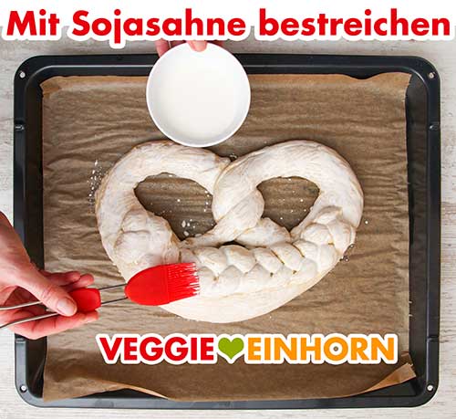 Mit einem Backpinsel bestreichen Bestreichen der Neujahrsbrezel mit Sojasahne