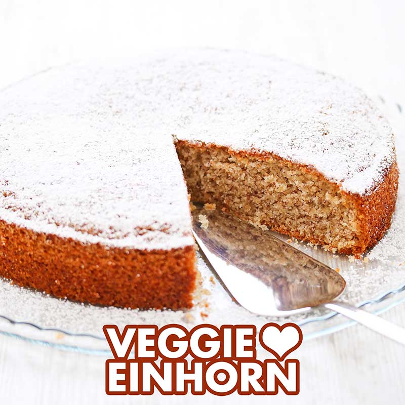 Saftiger veganer Nusskuchen aus der Springform Ein saftiger Nusskuchen auf einer Kuchenplatte mit einem Tortenheber