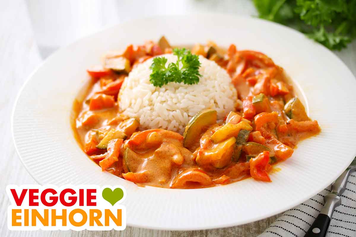 Paprika Curry mit Zucchini Veganes Curry mit Paprika, Zucchini und Reis auf einem Teller