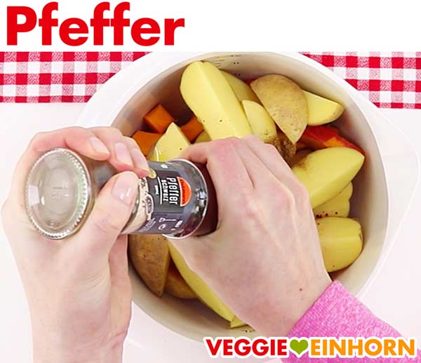 Die Kürbis- und Kartoffelspalten werden mit schwarzem Pfeffer gewürzt.