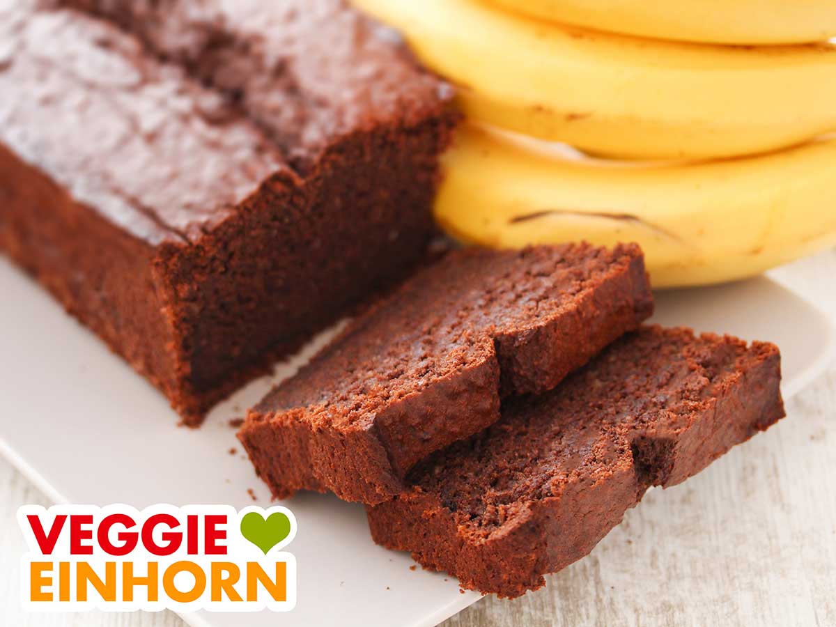 Ein angeschnittener Schoko Bananen Kuchen und zwei Kuchenstücke
