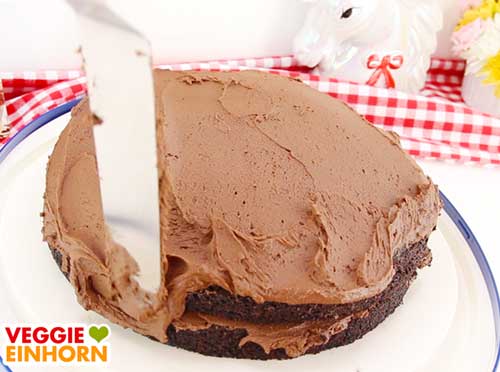 Schoko-Sahnecreme auf der veganen Torte verteilen Schoko-Sahnecreme auf der veganen Torte verteilen
