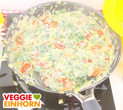 Tomaten, Spinat und veganer Frischkäse in der Pfanne