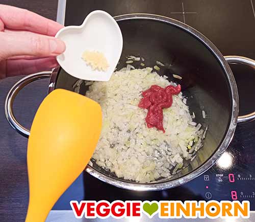 Tomatenmark und gepressten Knoblauch zufügen. Tomatenmark und Knoblauch werden hinzugefügt