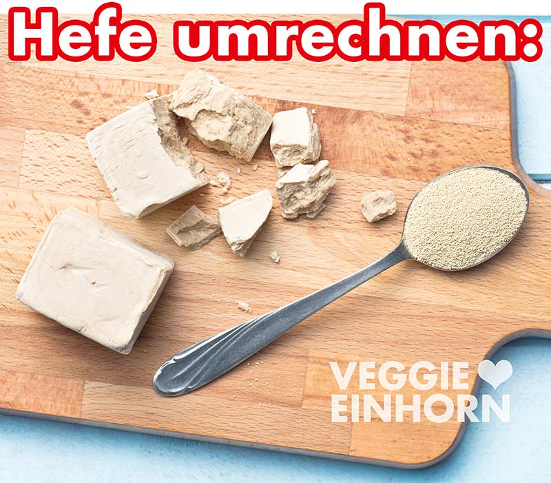 Ein Würfel Frischhefe und ein Teelöffel Trockenhefe auf einem Holzbrett