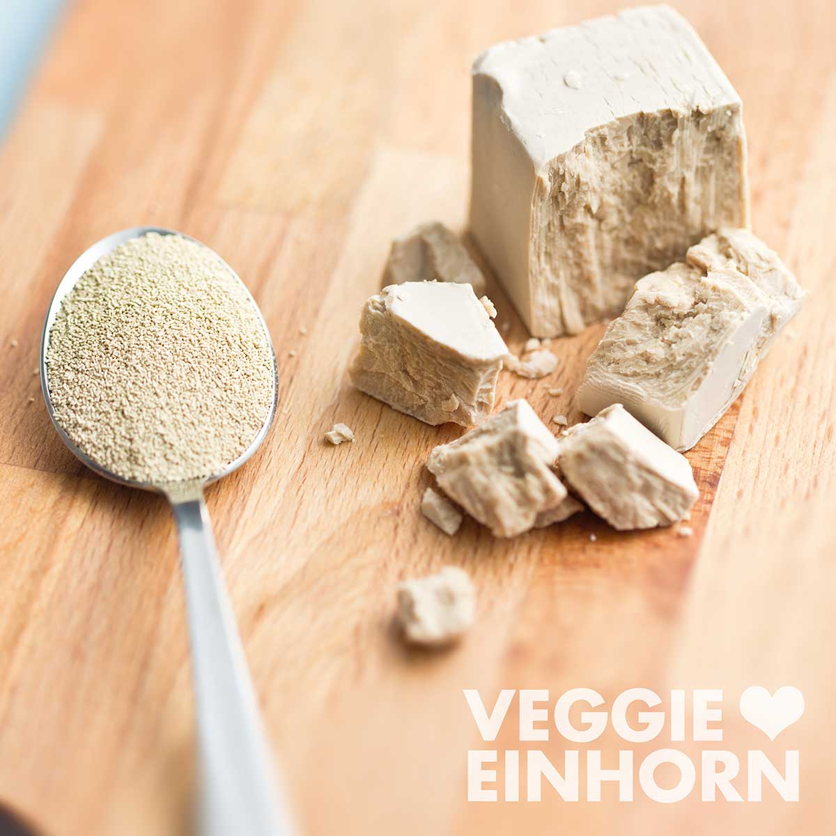 Ein Teelöffel mit Trockenhefe und ein Würfel frische Hefe