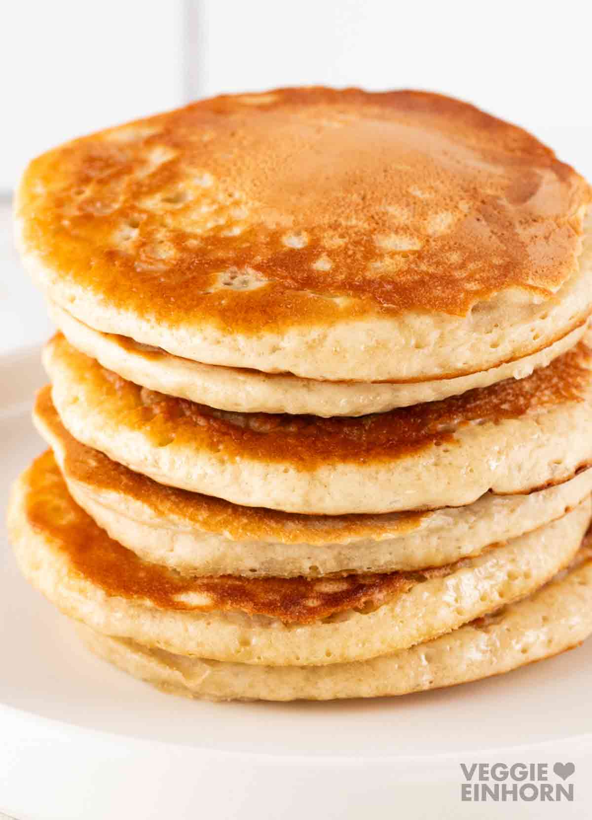 Ein Stapel fluffiger veganer Pancakes auf einem weißen Teller.