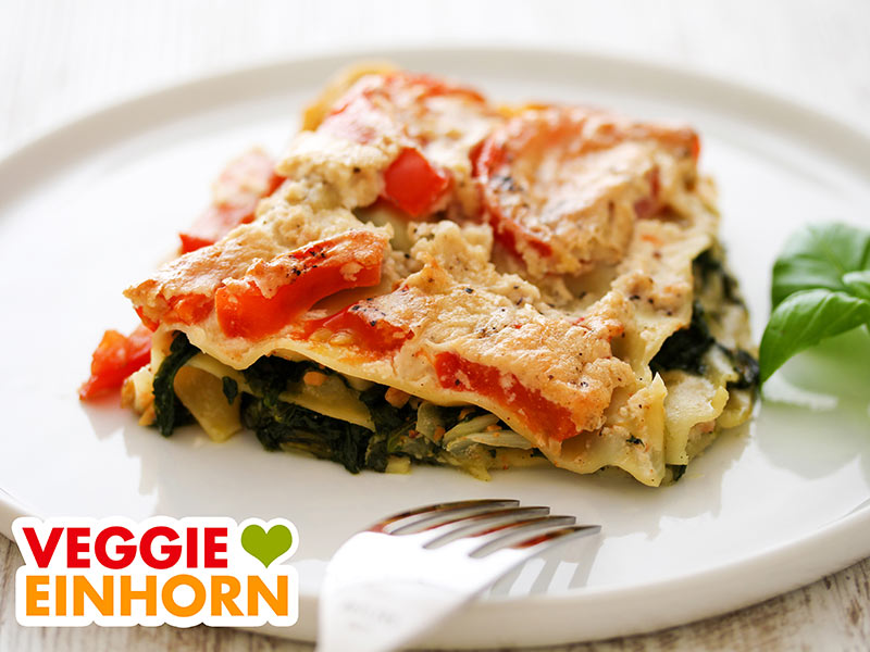 Eine Portion vegane Spinatlasagne mit Tomaten auf einem Teller