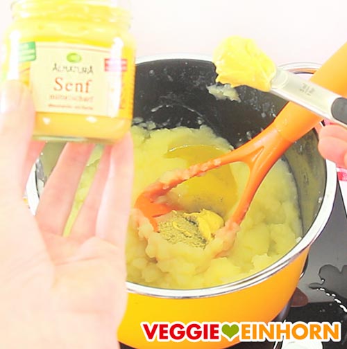 Veganen Senf zum Kartoffelbrei zufügen