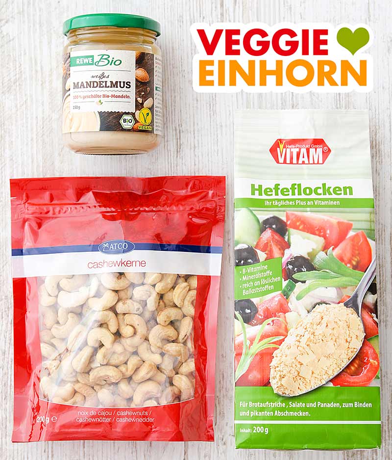 Ein Glas weißes Mandelmus, eine Packung Cashewkerne, eine Tüte Hefeflocken