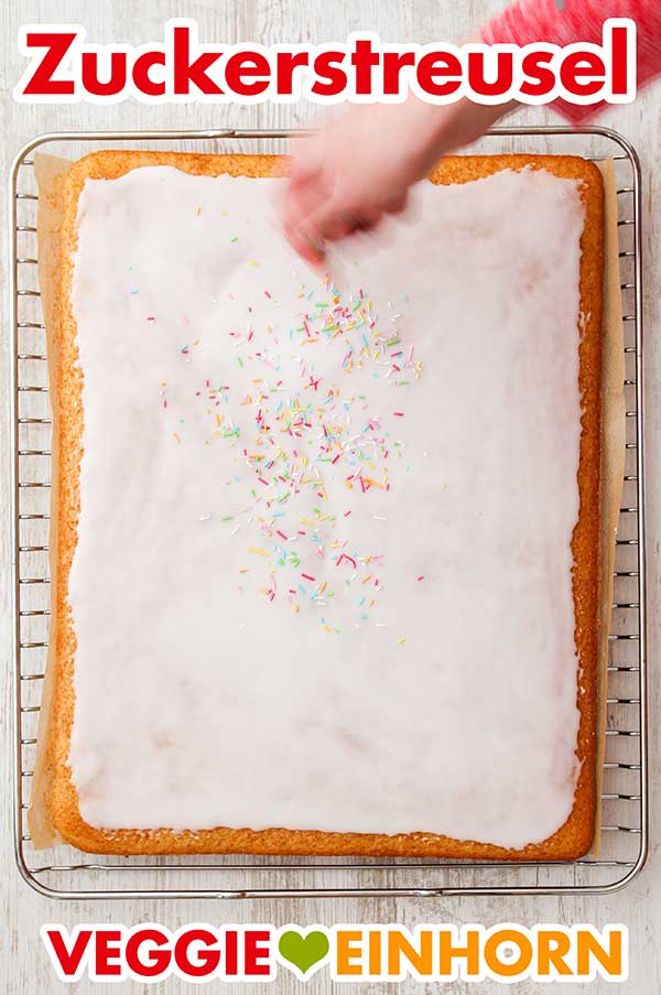 Bunte Zuckerstreusel für den Konfetti Kuchen Zuckerstreusel auf dem Puderzuckerguss verteilen