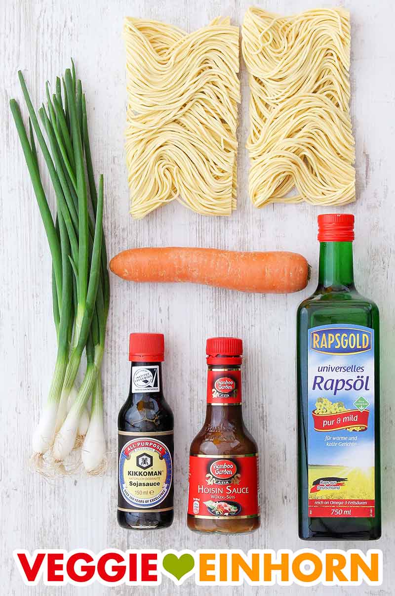 Frühlingszwiebeln, Diamond Quick Cooking Noodles, Möhre, Kikkoman Sojasauce, Bamboo Garden Hoisin Sauce, Rapsgold Universelles Rapsöl Die Zutaten für chinesische gebratene Nudeln liegen auf einem Tisch