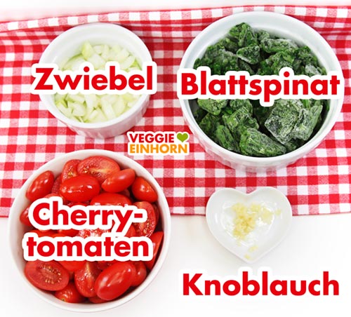 Gewürfelte Zwiebeln, tiefgefrorener Blattspinat, halbierte Cherrytomaten und gepresster Knoblauch