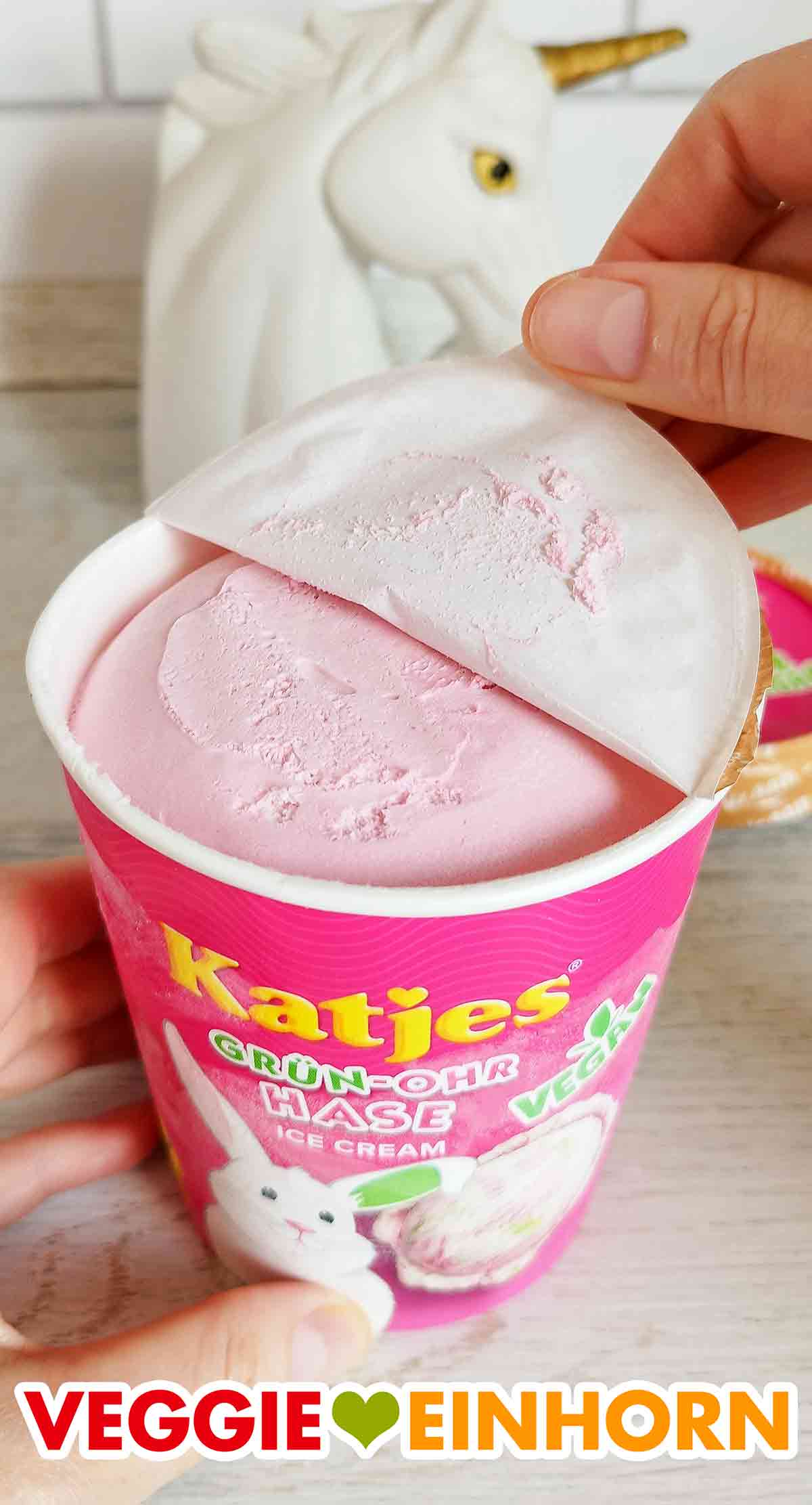 Die oberste Eis Schicht ist rosa. Die Deckelfolie des veganen Katjes Grün Ohr Hasen Eis wird abgezogen.