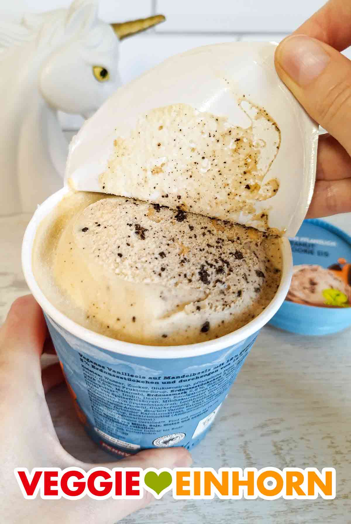 Abziehen der Deckelfolie des veganen Peanut Cookie Eis von Penny Food for Future. Die Folie des Eisbechers mit veganem Peanut Cookie Eis wird abgezogen.