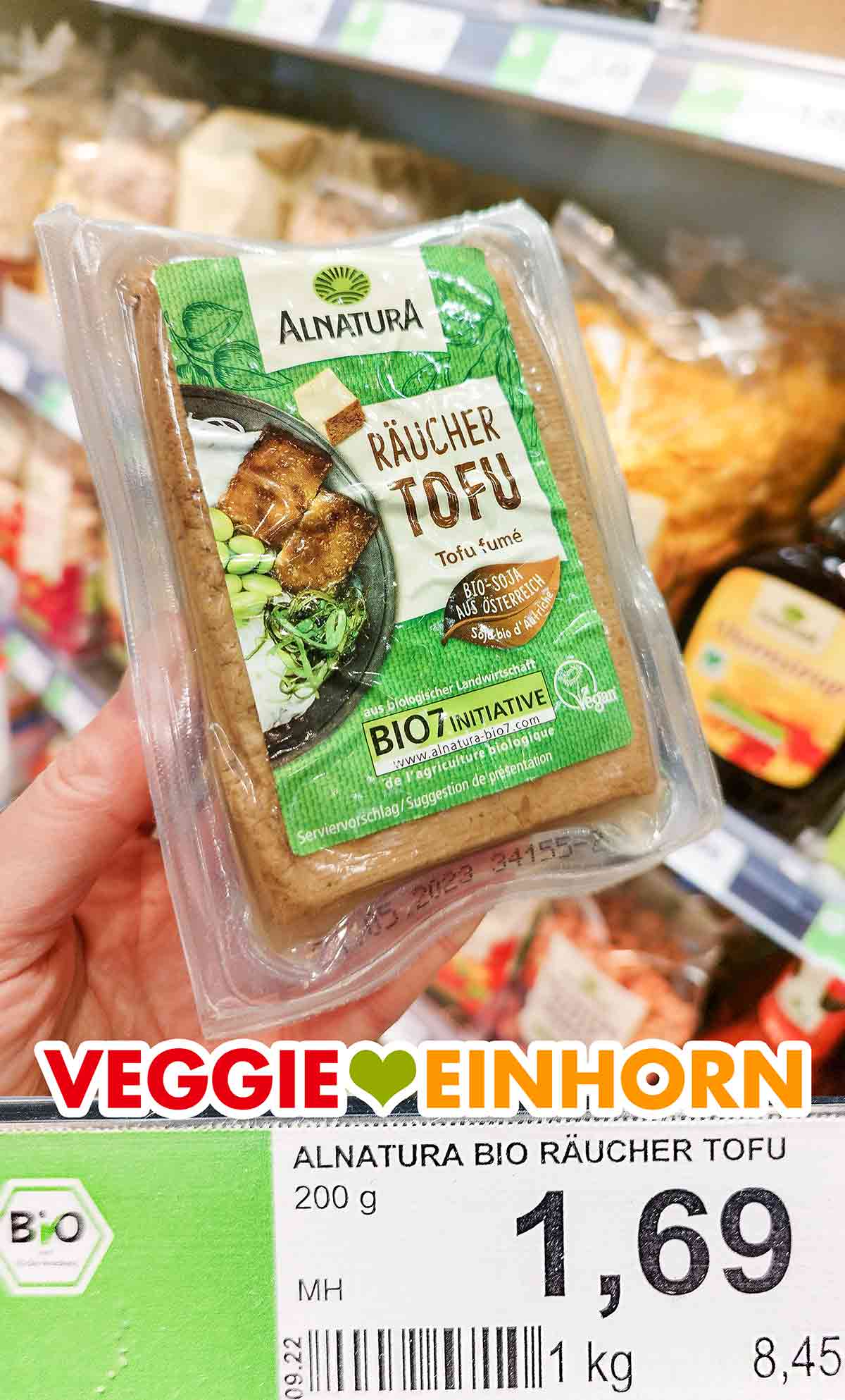 Bei Rossmann kostet der ungekühlte Räuchertofu von Alnatura 1,69 Euro. Eine Hand hält eine Packung ungekühlten Alnatura Räuchertofu