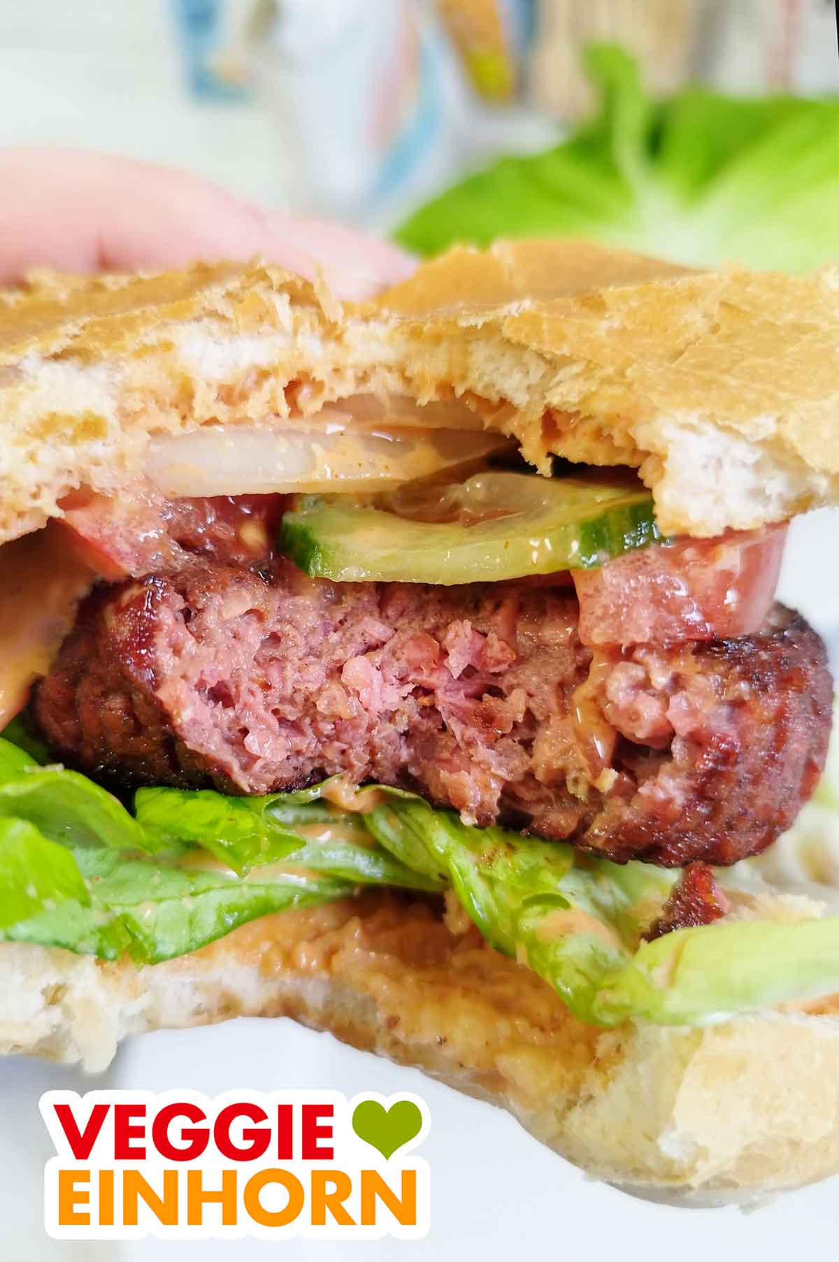 Der Patty hat eine authentische faserige Fleischstruktur. Eine Hand hält den angebissenen burger mit einem Patty von Food for Future by Penny