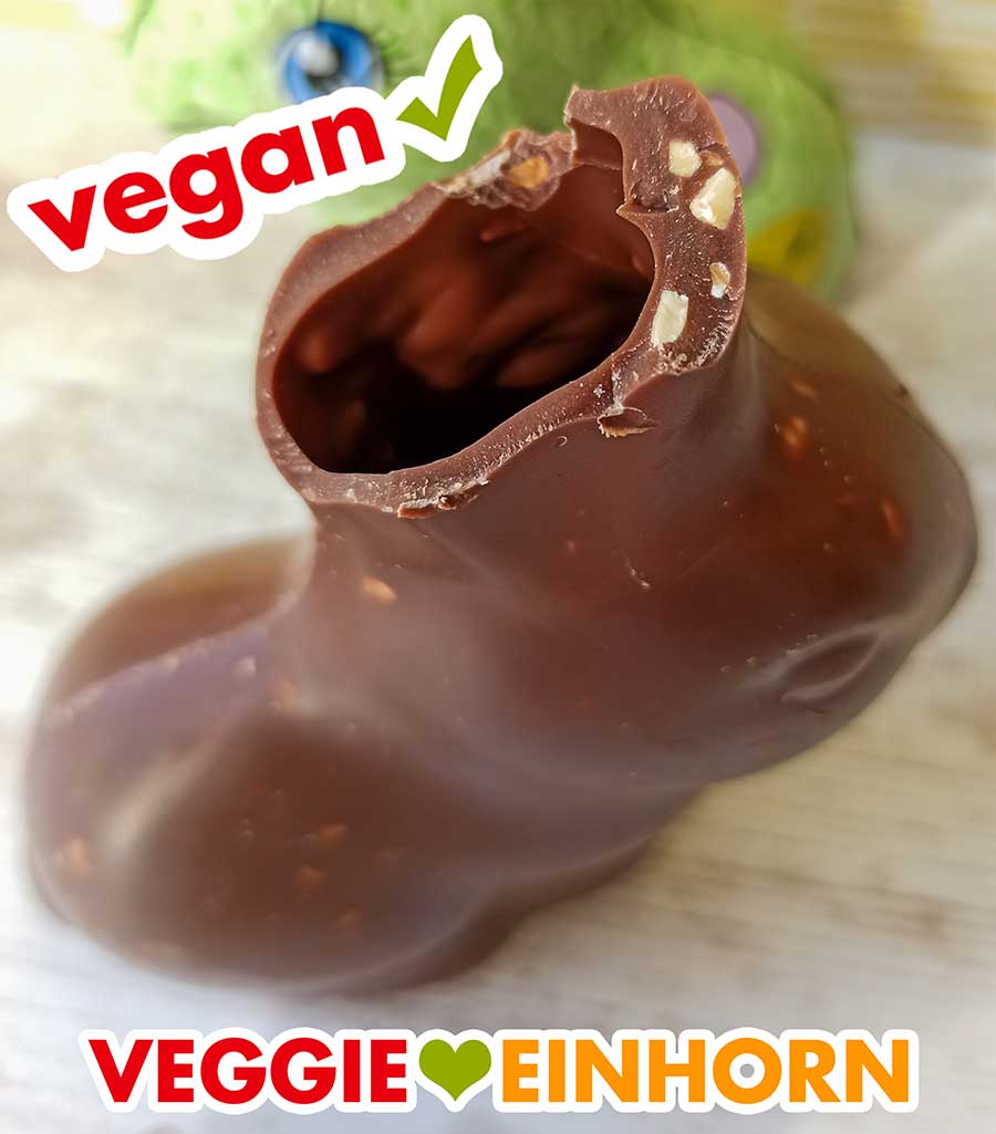 In der veganen Schokolade sind kleine Stückchen von Haselnüssen. Angebissener veganer Schoko Osterhase mit Nussstückchen