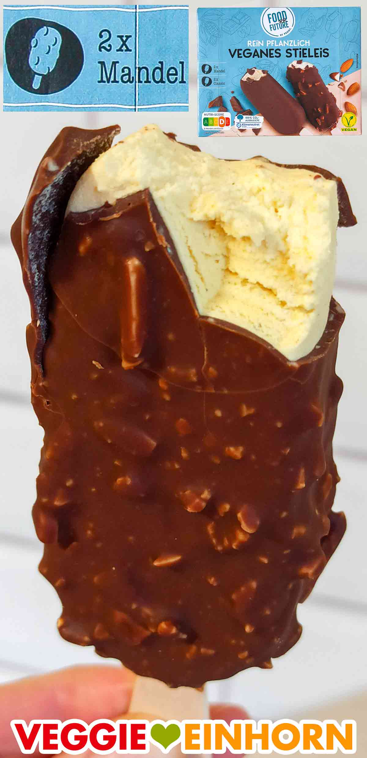 Das vegane Mandel Eis von Penny hat Mandelstückchen in der Schokolade. Angebissenes veganes Stieleis Mandel von Food for Future
