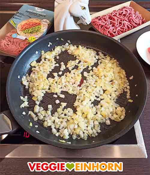 Die Zwiebelwürfel braten in der Pfanne. Angebratene Zwiebelwürfel in der Bratpfanne