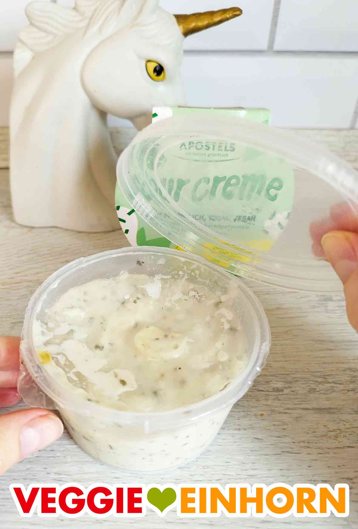 Entfernen des Plastikdeckels Der Deckel der veganen Sour Creme von Apostels wird geöffnet