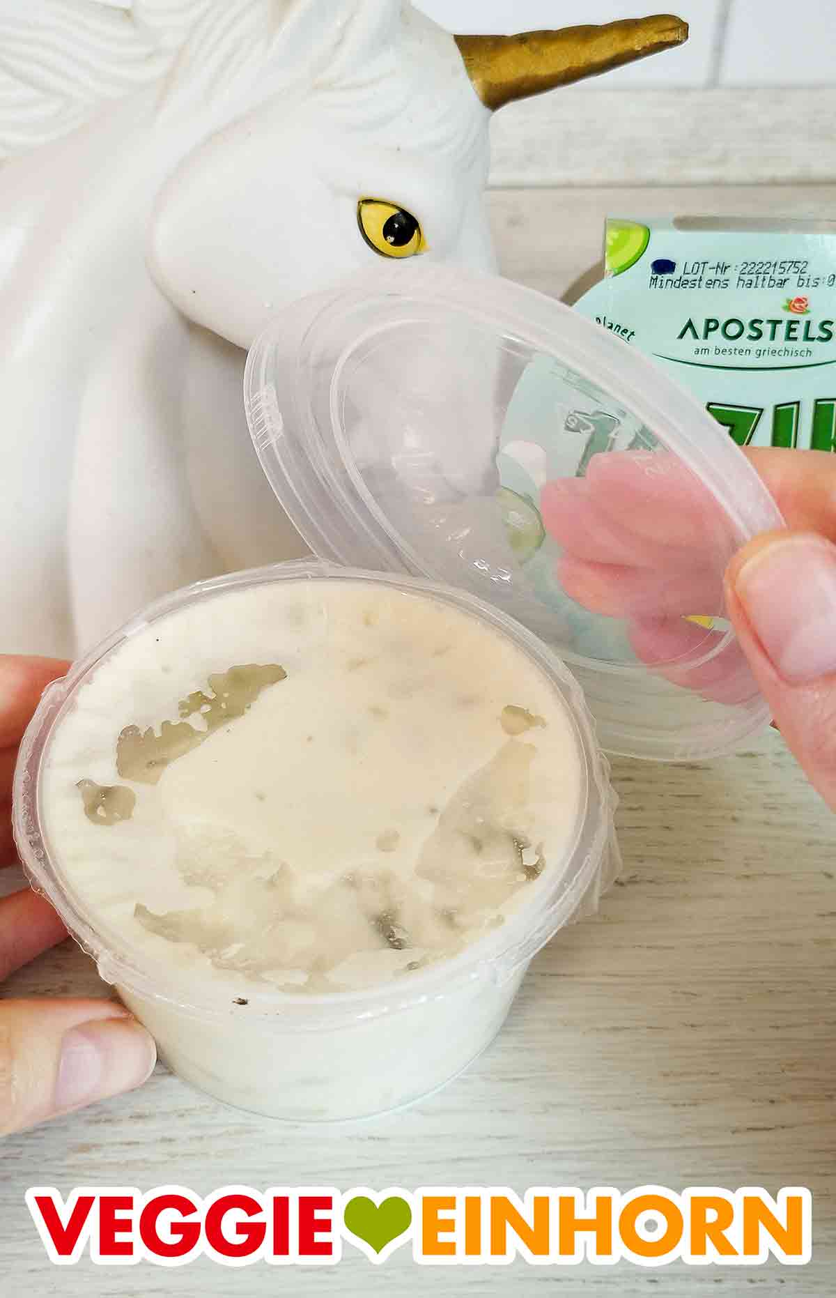 Der vegane Zaziki von Apostels wird geöffnet. Öffnen des Bechers mit veganem Zaziki von Apostels