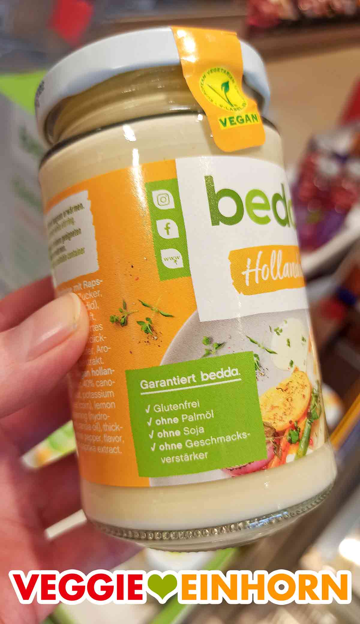 Die bedda Sauce Hollandaise ist vegan, glutenfrei, ohne Palmöl, ohne Soja und ohne Geschmacksverstärker. Eine Hand hält ein Glas vegane Sauce Hollandaise von bedda