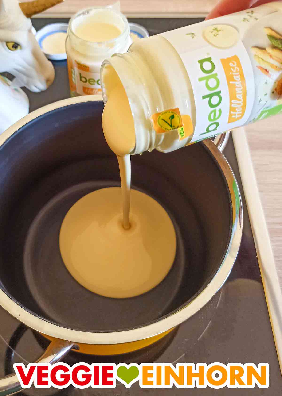 Die bedda Sauce Hollandaise wird in einen Kochtopf gegeben. Die vegane Sauce Hollandaise von bedda wird aus dem Glas in den Topf gegossen