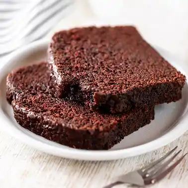 Zwei Stücke veganer Schokokuchen auf einem Teller, davor liegt eine Kuchengabel.