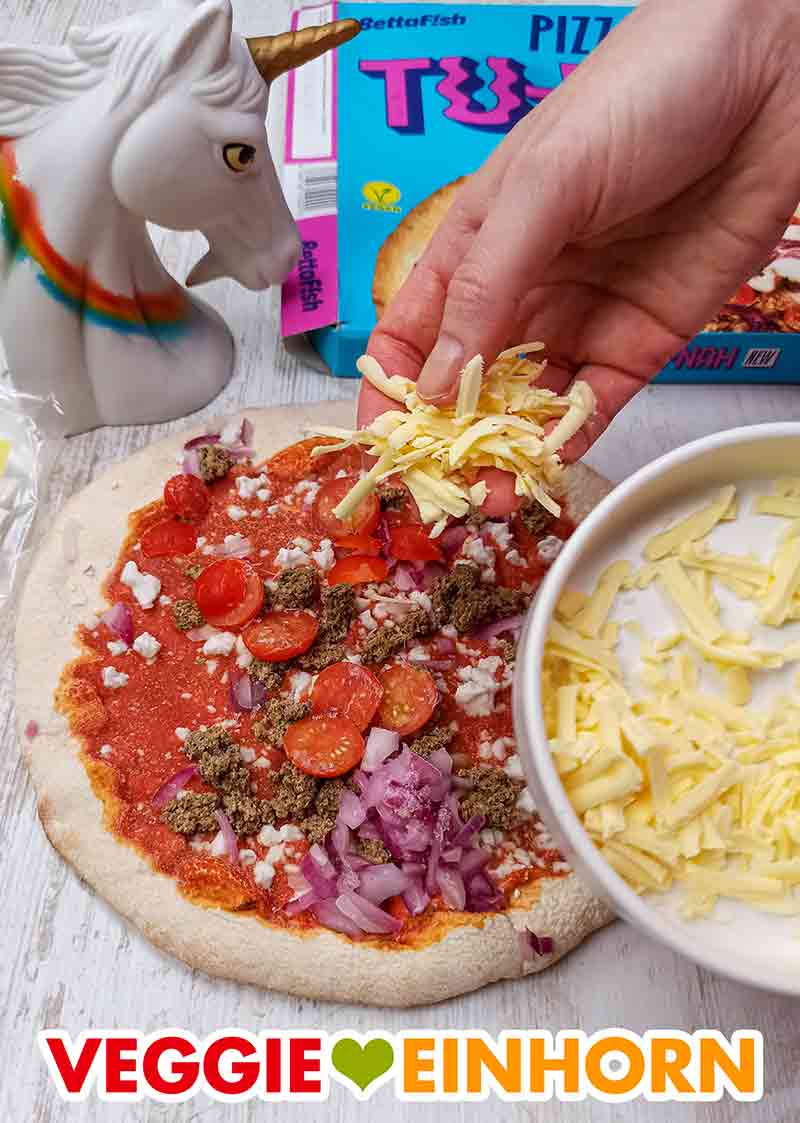 Das geriebene Veganz Genießerstück wird auf die gefrorene Tu-Nah Pizza gestreut. Die vegane Thunfisch Pizza wird mit geriebenem veganen Käse bestreut
