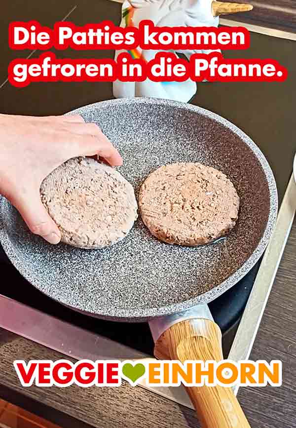 Die Patties kommen ohne Auftauen tiefgekühlt in die Pfanne. Zwei tiefgekühlte vegane Burger Patties in der Pfanne.