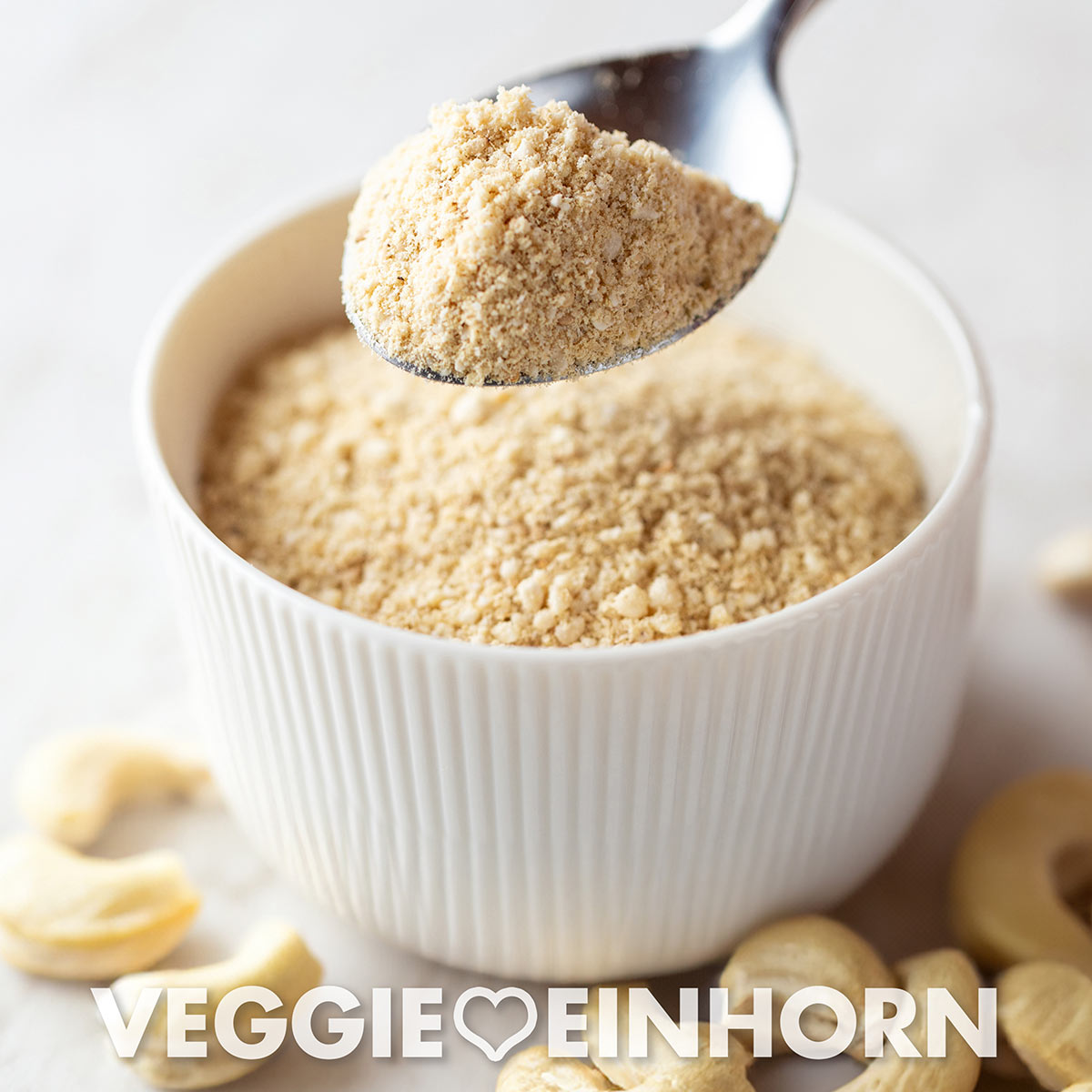 Veganer Cashew Parmesan-Ersatz in einer Schale und auf einem Löffel