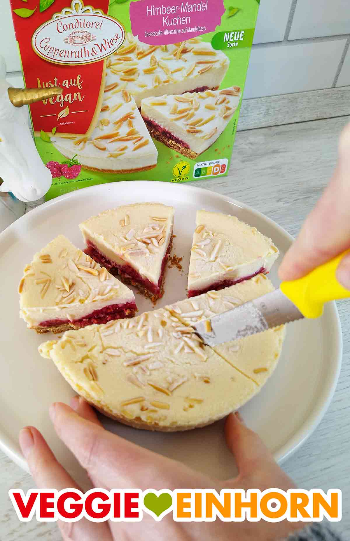 Aufschneiden der Stücke Der vegane Himbeer Mandel Cheesecake von Coppenrath und Wiese wird mit einem Messer in Stücke geschnitten
