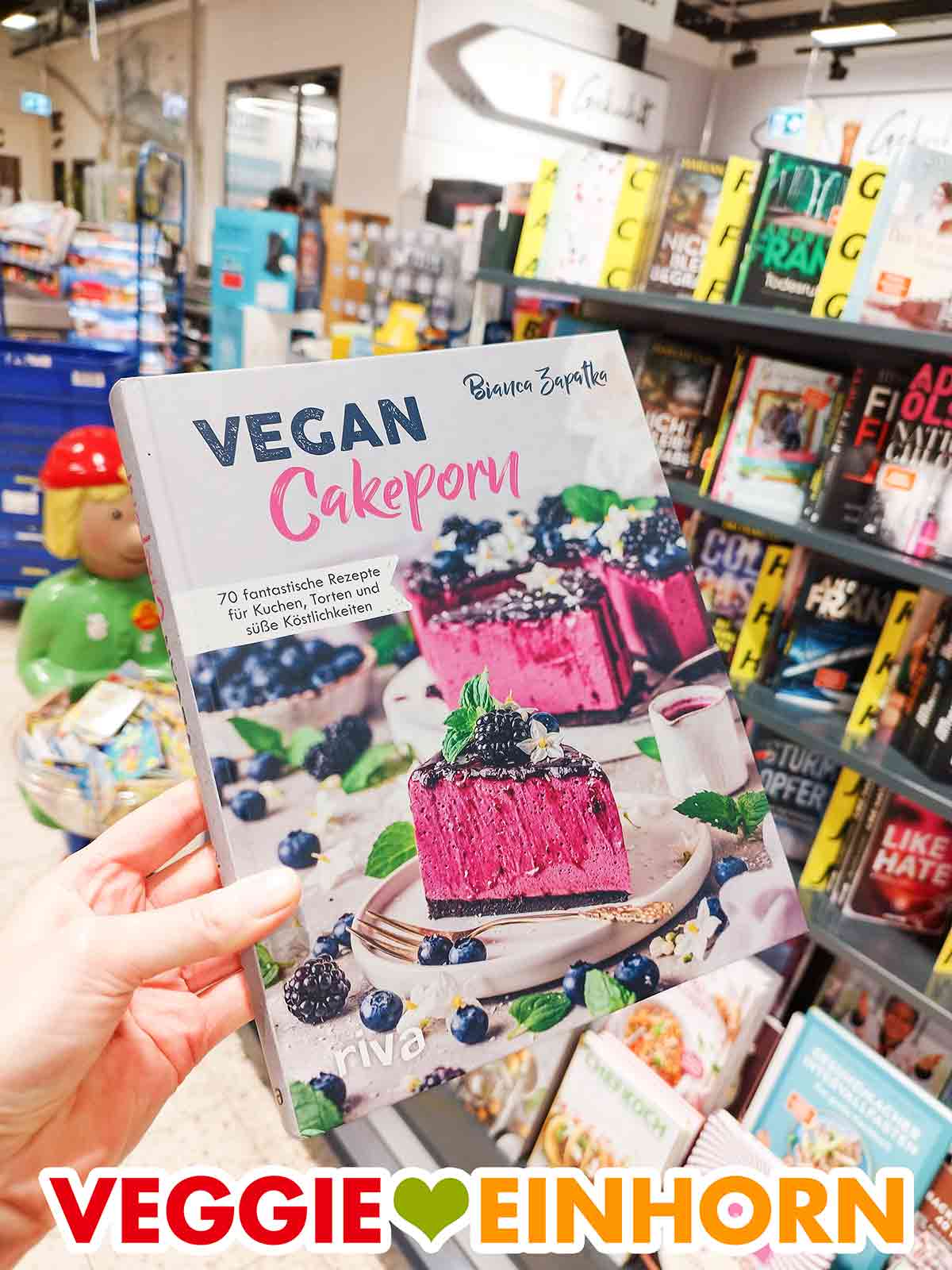 Ich habe das Buch Vegan Cakeporn von Bianca Zapatka im Supermarkt gekauft. Eine Hand hält das Buch Vegan Cakeporn von Bianca Zapatka im Marktkauf