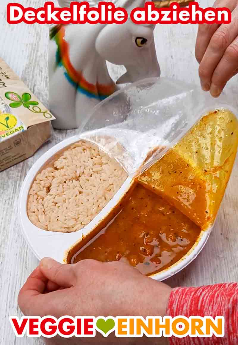 Nach dem Erhitzen wird die Folie abgezogen. Die Deckelfolie der Menüschale des veganen Fertiggerichtes wird abgezogen.
