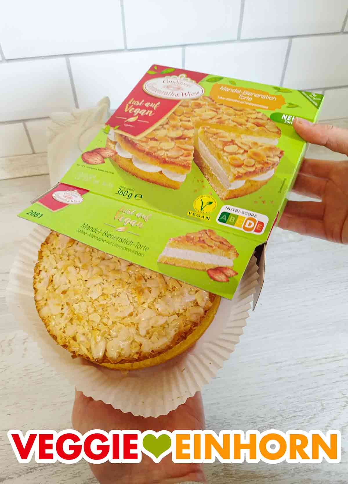 Auspacken der veganen Mandel-Bienenstich-Torte. Der tiefgekühlte vegane Bienenstich von Coppenrath und Wiese wird aus der Packung genommen.